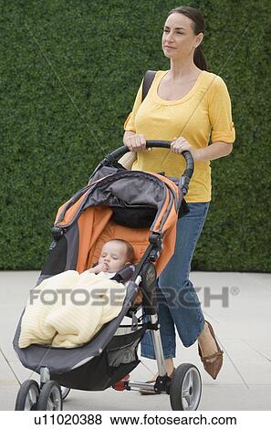 Mother walking baby son in stroller View Large Photo Image Stock Photo - Mother walking baby son in stroller. Fotosearch