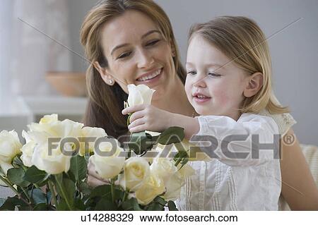 Stock Photo - Mother watching daughter arrange flowers. Fotosearch