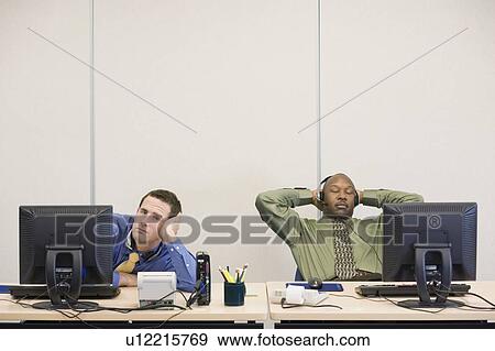 Stock Photo - Multi-ethnic businessmen sitting at desks. Fotosearch