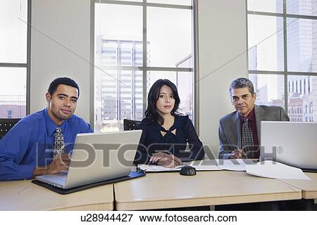 Stock Photo - Multi-ethnic businesspeople at table. Fotosearch