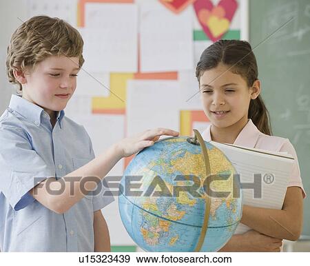 Stock Photo - Multi-ethnic school children looking at globe. Fotosearch