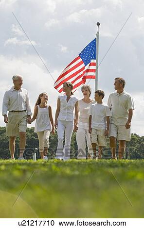 Stock Image - Multi-generational family walking in front of American flag. Fotosearch