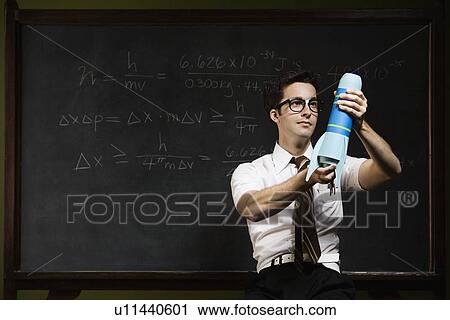 Nerdy man holding rocket model in front of blackboard View Large Photo Image Stock Image - Nerdy man holding rocket model in front of blackboard. Fotosearch