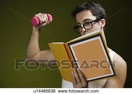 Stock Photo - Nerdy man lifting weight and reading book. Fotosearch