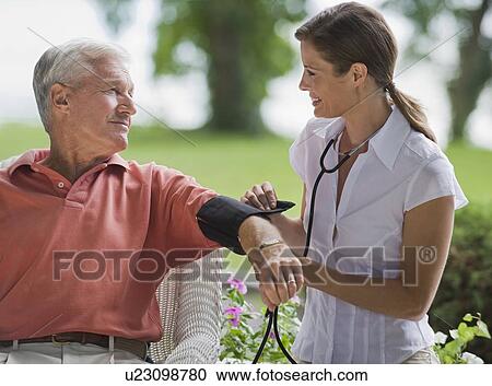 Stock Image - Nurse checking senior man’s blood pressure. Fotosearch