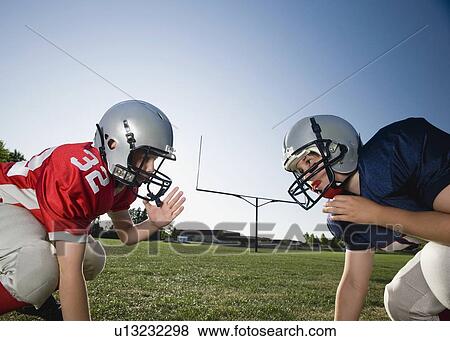 Stock Photo - Opposing football players facing at line of scrimmage. Fotosearch