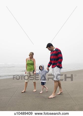 Parents holding hands with son on beach View Large Photo Image Stock Photo - Parents holding hands with son on beach. Fotosearch