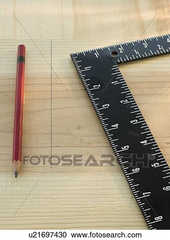 Stock Image - Pencil and carpenter’s rule on wood plank. Fotosearch