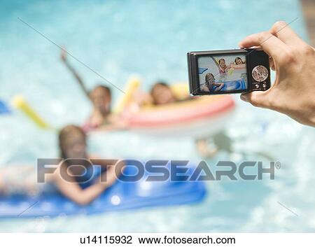 Stock Image - Person photographing girls in swimming pool. Fotosearch