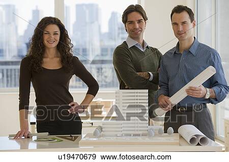 Stock Photo - Portrait of architects with building model and blueprints. Fotosearch