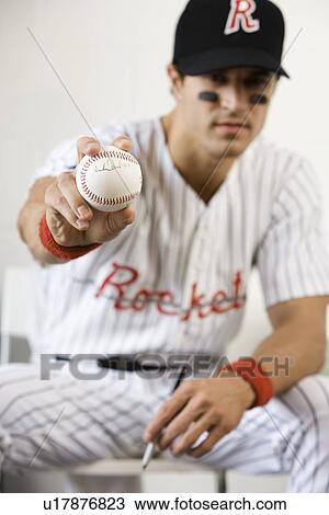 Stock Image - Portrait of baseball player holding autographed baseball. Fotosearch