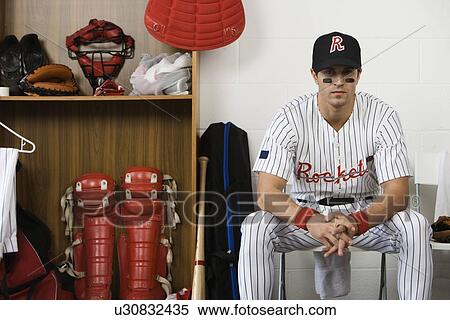 Stock Photography - Portrait of baseball player sitting in locker room. Fotosearch