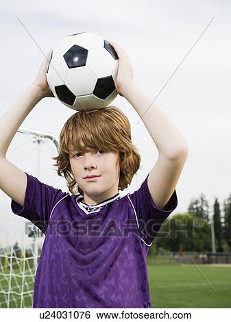 Stock Photograph - Portrait of boy holding soccer ball on head. Fotosearch