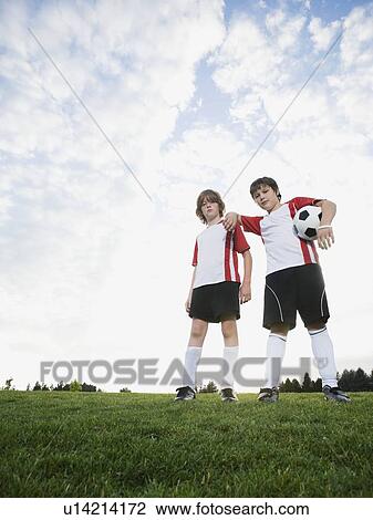 Stock Image - Portrait of boys in soccer uniforms holding ball. Fotosearch