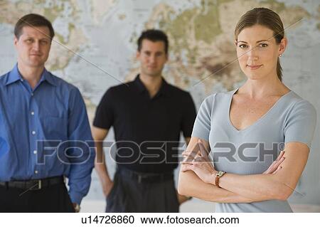 Stock Image - Portrait of business people standing in front of map. Fotosearch