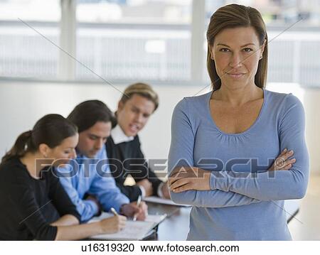 Stock Image - Portrait of businesswoman with business people in background. Fotosearch