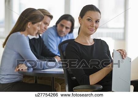Stock Photograph - Portrait of businesswoman with business people in background. Fotosearch