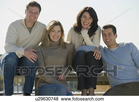 Stock Photo - Portrait of couples sitting on outdoor bench. Fotosearch