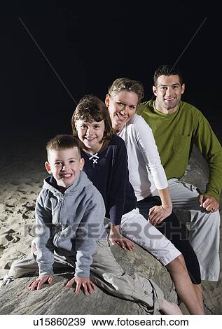 Portrait of family sitting on driftwood at beach View Large Photo Image Stock Photo - Portrait of family sitting on driftwood at beach. Fotosearch