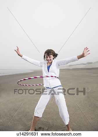 Stock Image - Portrait of girl with hula hoop on beach. Fotosearch