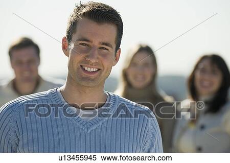 Stock Photography - Portrait of man with friends in background. Fotosearch