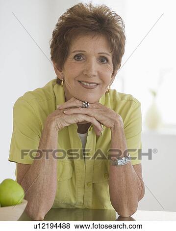 Stock Photo - Portrait of senior woman leaning on counter. Fotosearch
