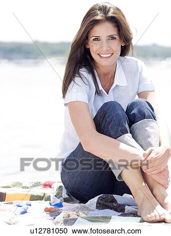 Stock Image - Portrait of woman sitting on blanket. Fotosearch