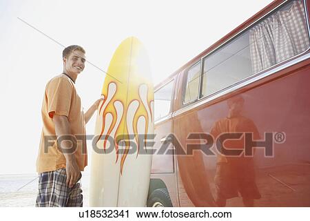 Portrait of young man holding surfboard near van View Large Photo Image Stock Image - Portrait of young man holding surfboard near van. Fotosearch
