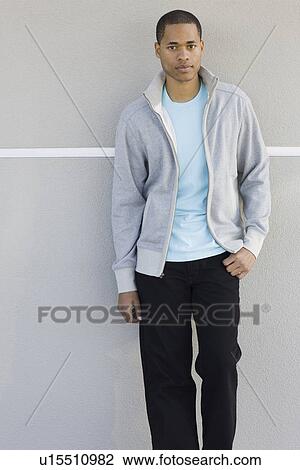 Stock Image - Portrait of young man leaning against wall. Fotosearch