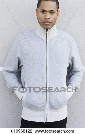Stock Image - Portrait of young man leaning against wall. Fotosearch