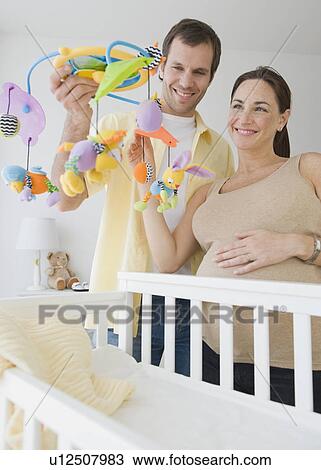 Pregnant Hispanic couple holding mobile over crib View Large Photo Image Stock Image - Pregnant Hispanic couple holding mobile over crib. Fotosearch