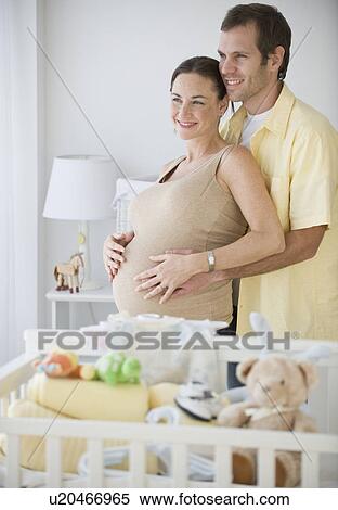 Stock Photography - Pregnant Hispanic couple hugging. Fotosearch