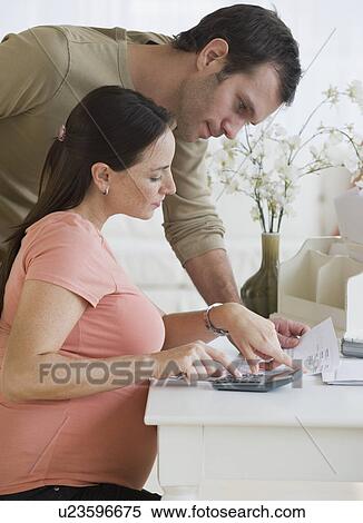 Stock Photography - Pregnant Hispanic couple paying bills. Fotosearch