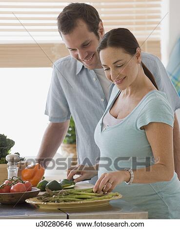Pregnant Hispanic couple preparing food View Large Photo Image Stock Photograph - Pregnant Hispanic couple preparing food. Fotosearch