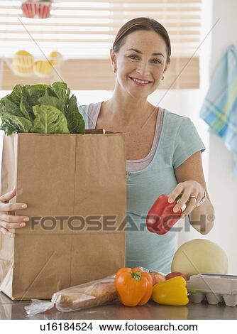 Pregnant Hispanic woman unpacking groceries View Large Photo Image Picture - Pregnant Hispanic woman unpacking groceries. Fotosearch