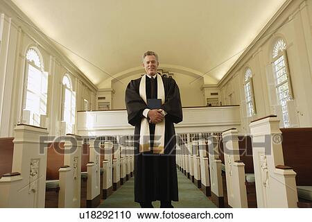Stock Image - Priest holding bible in church. Fotosearch