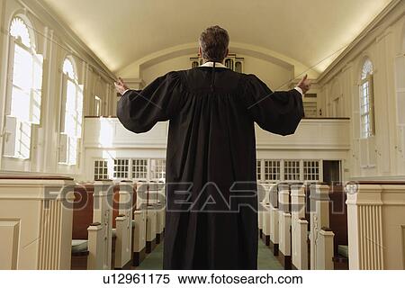 Stock Photography - Priest with arms raised in church. Fotosearch
