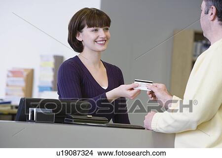 Receptionist accepting payment View Large Photo Image Picture - Receptionist accepting payment. Fotosearch