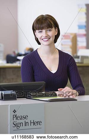Stock Image - Receptionist sitting at counter. Fotosearch