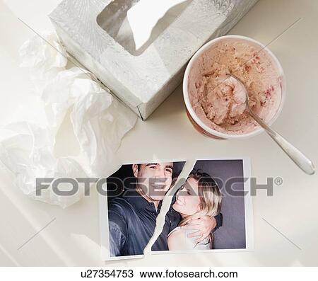 Stock Image - Ripped photograph next to ice cream and tissues. Fotosearch