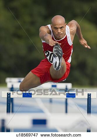 Runner jumping over hurdle View Large Photo Image Stock Photo - Runner jumping over hurdle. Fotosearch