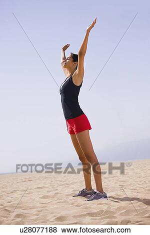 Stock Photo - Runner stretching on beach. Fotosearch