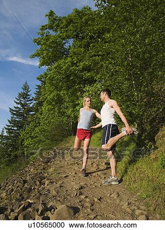 Stock Image - Runners stretching on rocky trail. Fotosearch