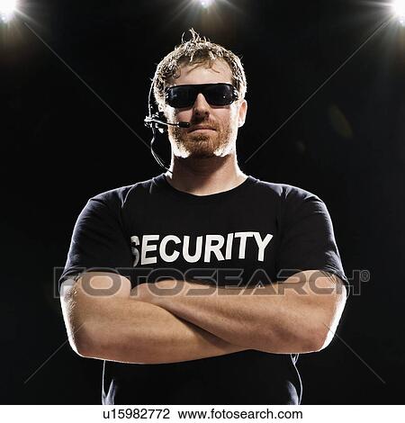 Stock Image - Security guard with headset posing with arms crossed. Fotosearch