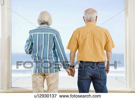 Stock Photo - Senior couple looking out window. Fotosearch