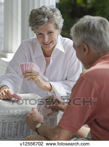 Stock Image - Senior couple playing card game on porch. Fotosearch