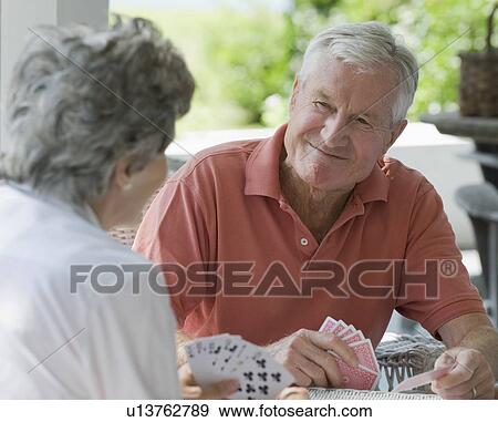 Stock Photo - Senior couple playing card game on porch. Fotosearch