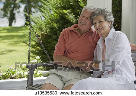 Stock Image - Senior couple sitting on porch swing. Fotosearch