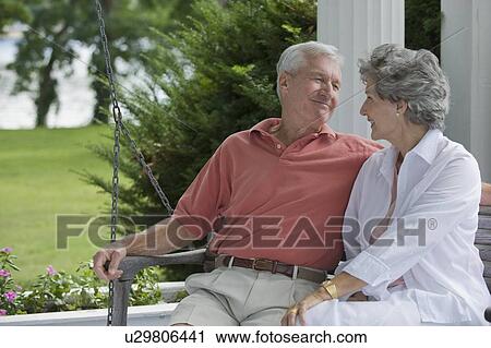 Stock Image - Senior couple sitting on porch swing. Fotosearch
