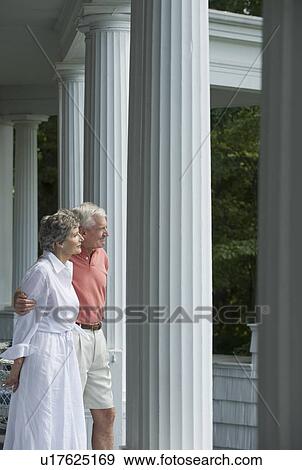 Stock Photo - Senior couple standing on front porch. Fotosearch